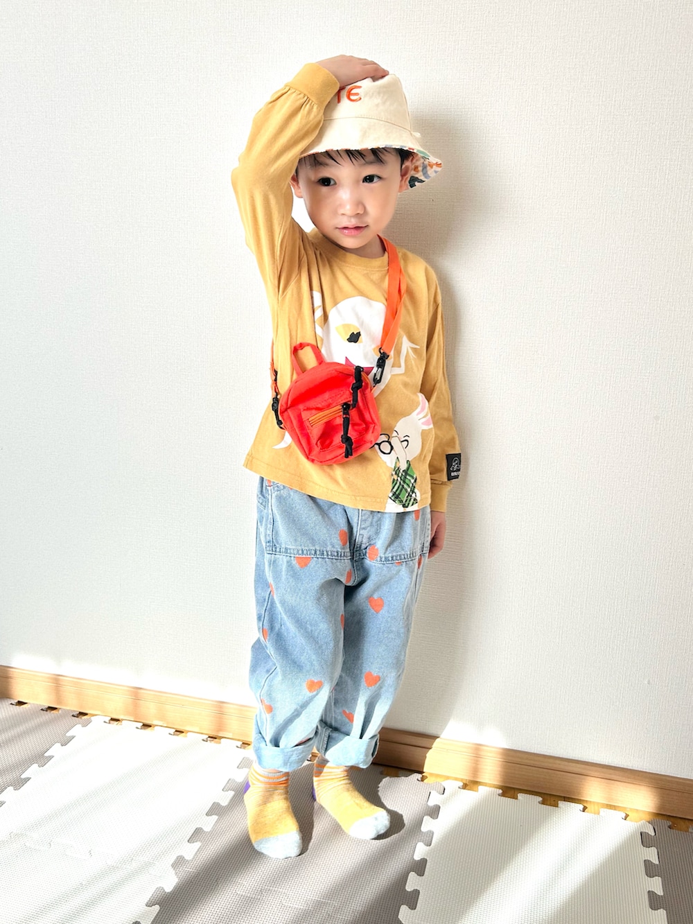 イエロー系のTシャツ/カットソー、ブルー系のデニムパンツ、オレンジ系のショルダーバッグを着用したキッズの春コーディネートの5枚目の写真