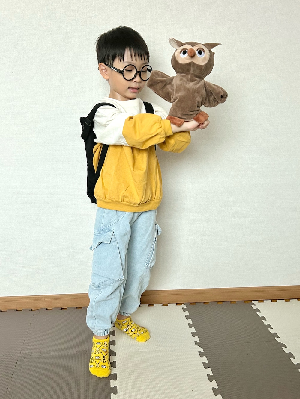 イエロー系のTシャツ/カットソー、ブルー系のデニムパンツ、ブラック系のバックパック/リュックを着用したキッズの秋コーディネートの4枚目の写真