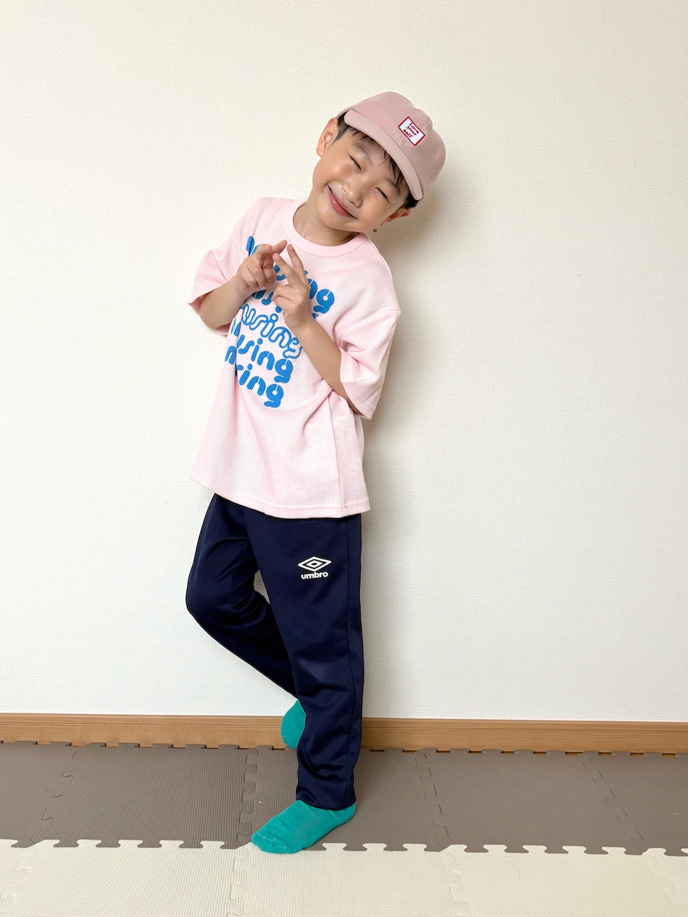 ピンク系のTシャツ/カットソー、ブルー系のジャージ、ブラウン系のポーチを着用したキッズの春コーディネートの3枚目の写真