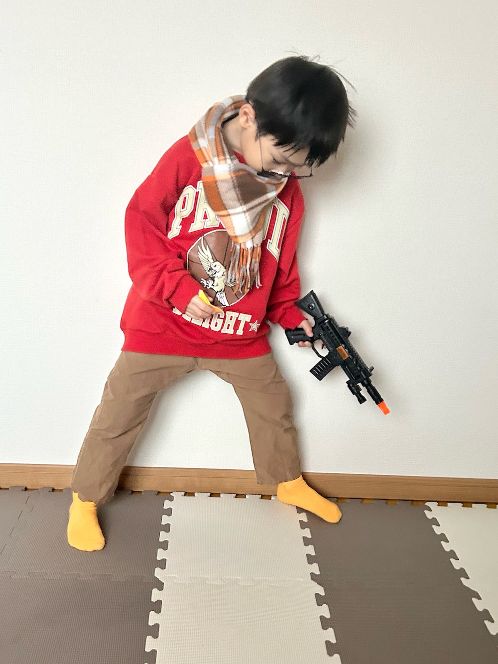 レッド系のスウェット、ブラウン系のパンツ、シルバー系のマフラーを着用したキッズの秋コーディネートの4枚目の写真