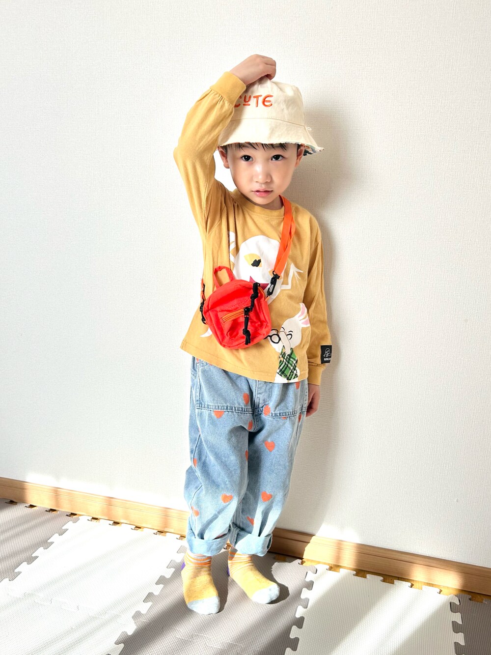 イエロー系のTシャツ/カットソー、ブルー系のデニムパンツ、オレンジ系のショルダーバッグを着用したキッズの春コーディネートの2枚目の写真