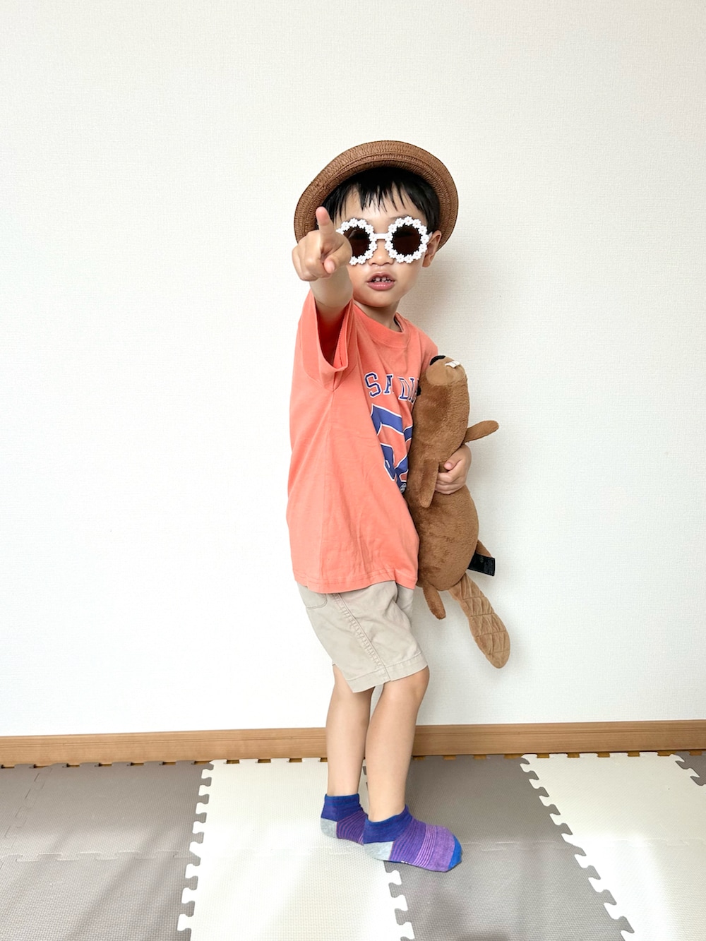 オレンジ系のTシャツ/カットソー、ベージュ系のチノパンツ、ブラウン系のハットを着用したキッズの夏コーディネートの2枚目の写真