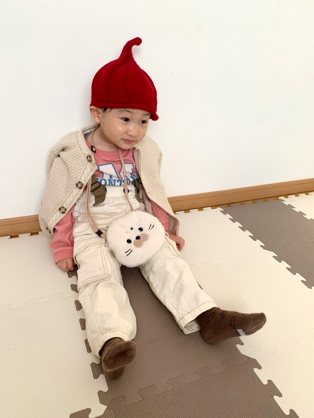 ピンク系のTシャツ/カットソー、ホワイト系のサロペット/オーバーオール、ベージュ系のカーディガン/ボレロを着用したキッズの冬コーディネートの3枚目の写真