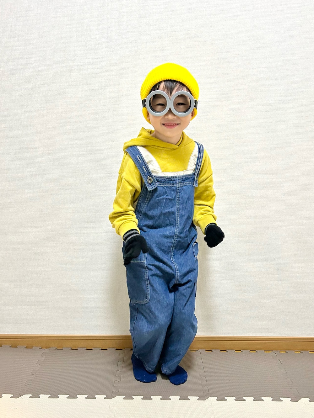 イエロー系のパーカー、ブルー系のサロペット/オーバーオール、グレー系のメガネを着用したキッズの秋コーディネートの3枚目の写真