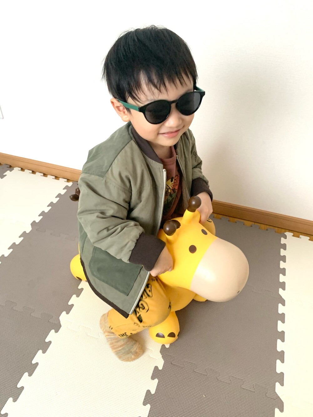 イエロー系のチノパンツ、グリーン系のジャケット/アウター、ブラウン系のスウェットを着用したキッズの冬コーディネートの2枚目の写真