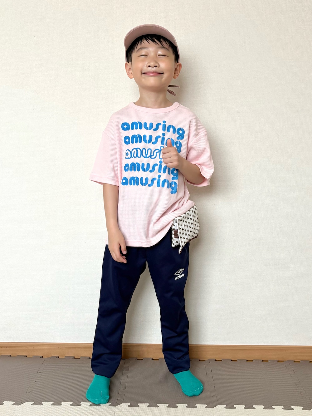 ピンク系のTシャツ/カットソー、ブルー系のジャージ、ブラウン系のポーチを着用したキッズの春コーディネートの2枚目の写真