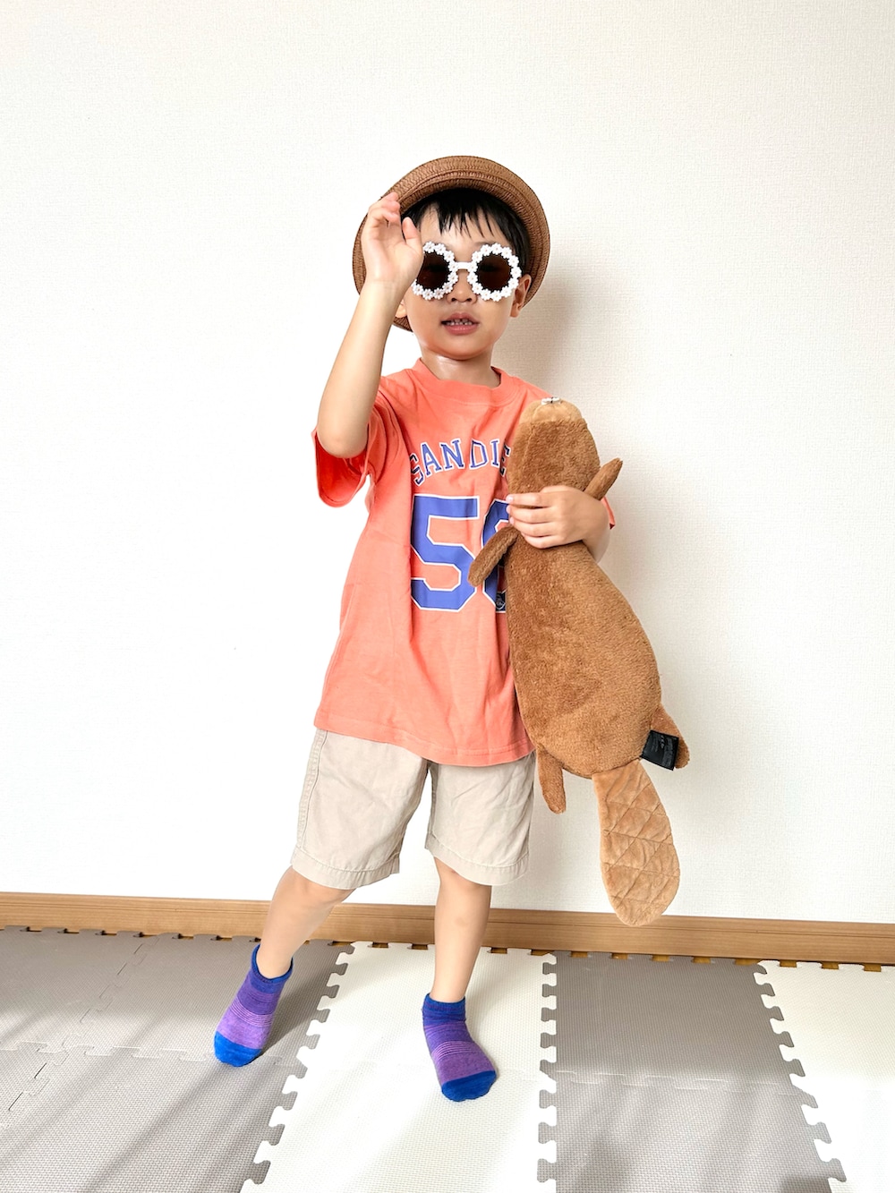 オレンジ系のTシャツ/カットソー、ベージュ系のチノパンツ、ブラウン系のハットを着用したキッズの夏コーディネートの5枚目の写真