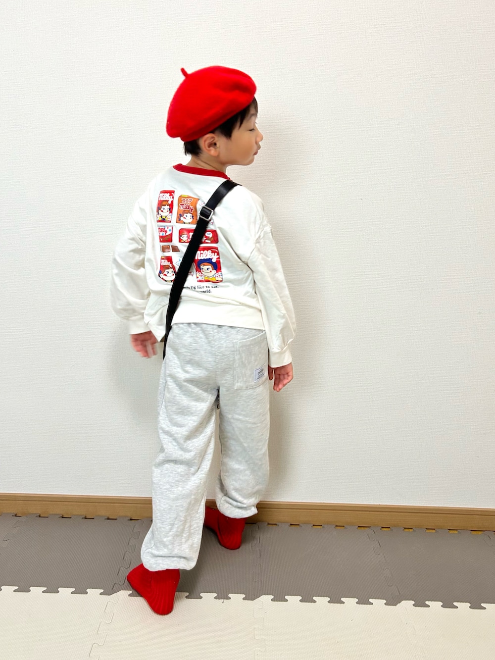 グレー系のスウェットパンツ、ホワイト系のスウェット、イエロー系のショルダーバッグを着用したキッズの秋コーディネートの2枚目の写真