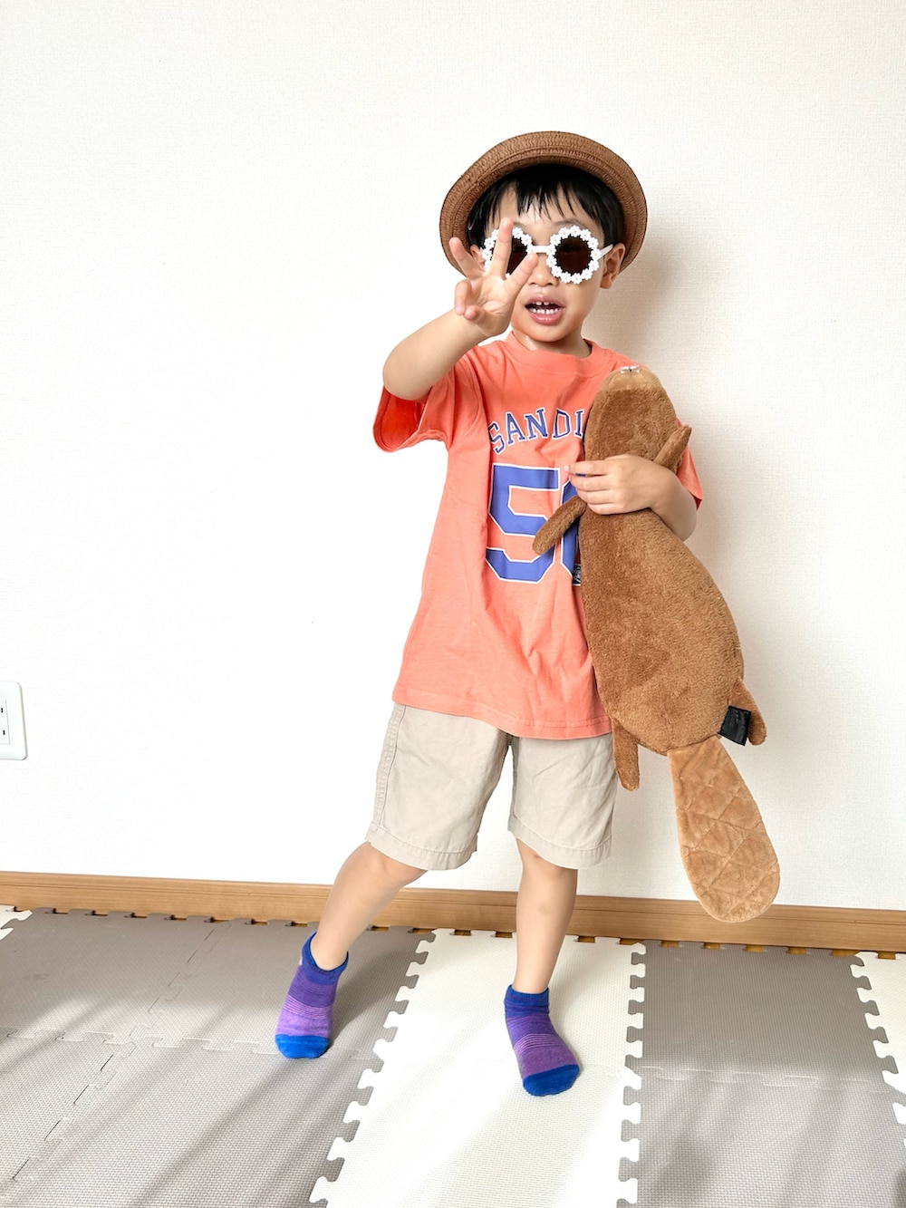 オレンジ系のTシャツ/カットソー、ベージュ系のチノパンツ、ブラウン系のハットを着用したキッズの夏コーディネートの4枚目の写真