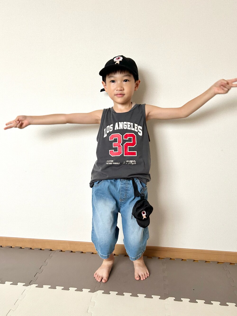 ブルー系のデニムパンツ、グレー系のタンクトップ、ブラック系のバッグを着用したキッズの夏コーディネートの3枚目の写真