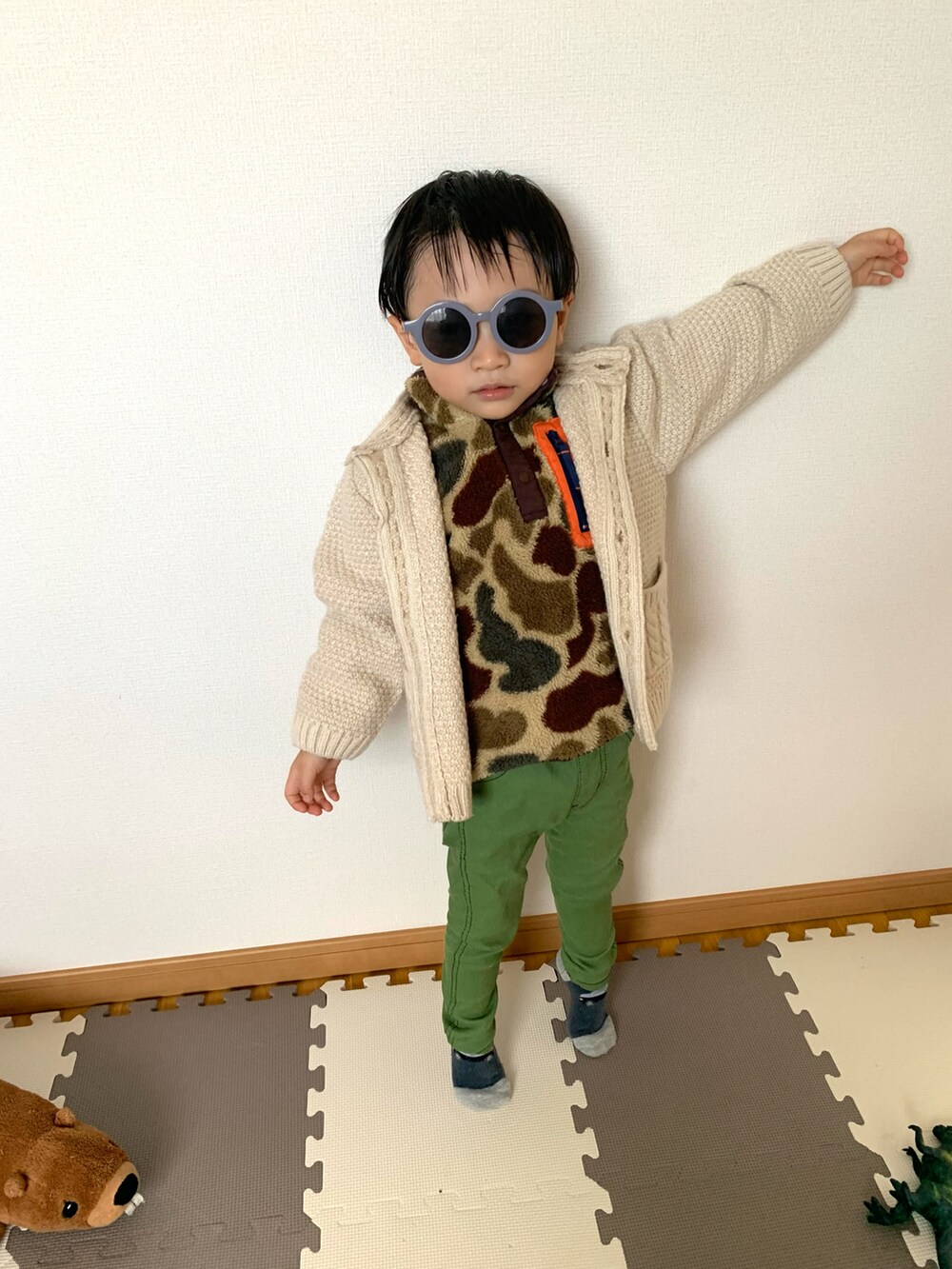 グリーン系のトップス、グリーン系のチノパンツ、ホワイト系のカーディガン/ボレロを着用したキッズの秋コーディネートの2枚目の写真