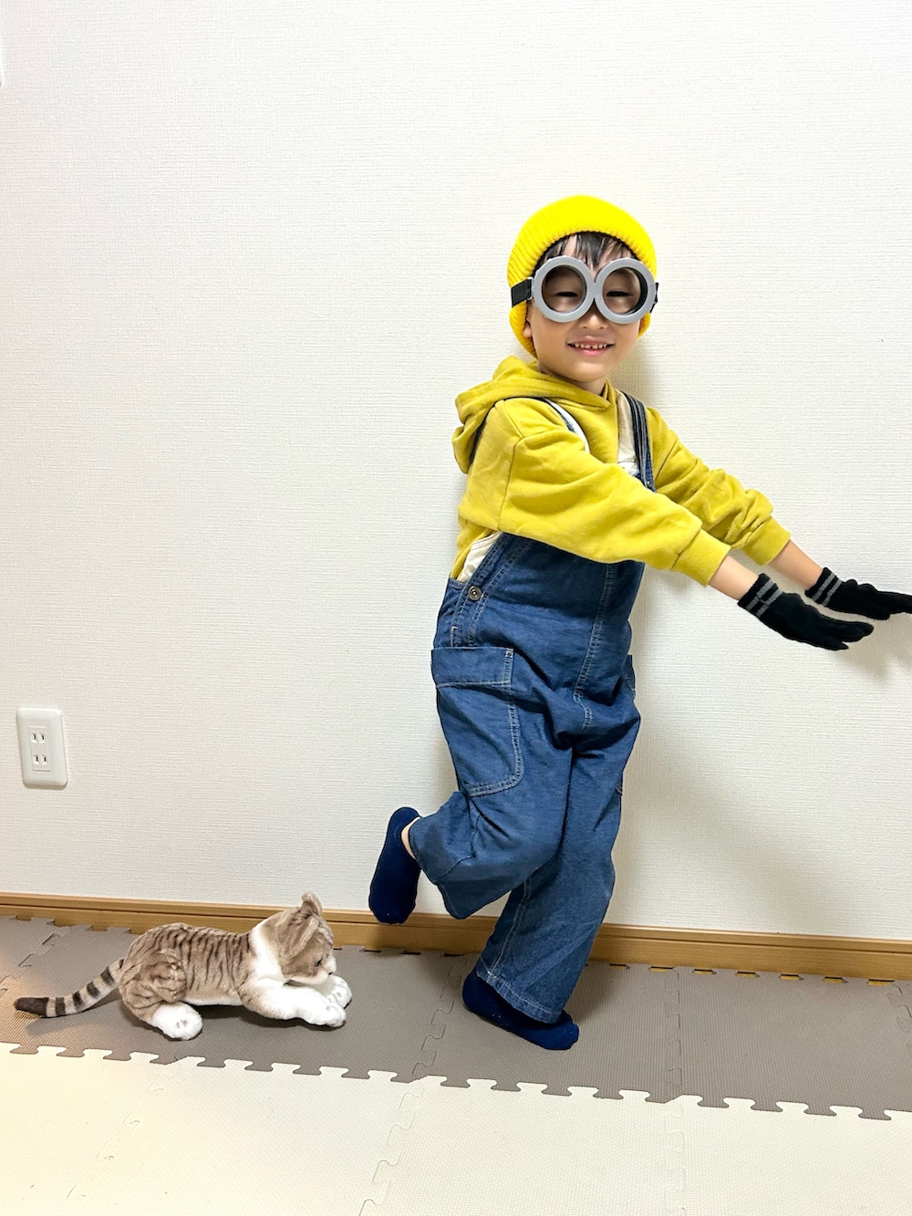 イエロー系のパーカー、ブルー系のサロペット/オーバーオール、グレー系のメガネを着用したキッズの秋コーディネートの4枚目の写真