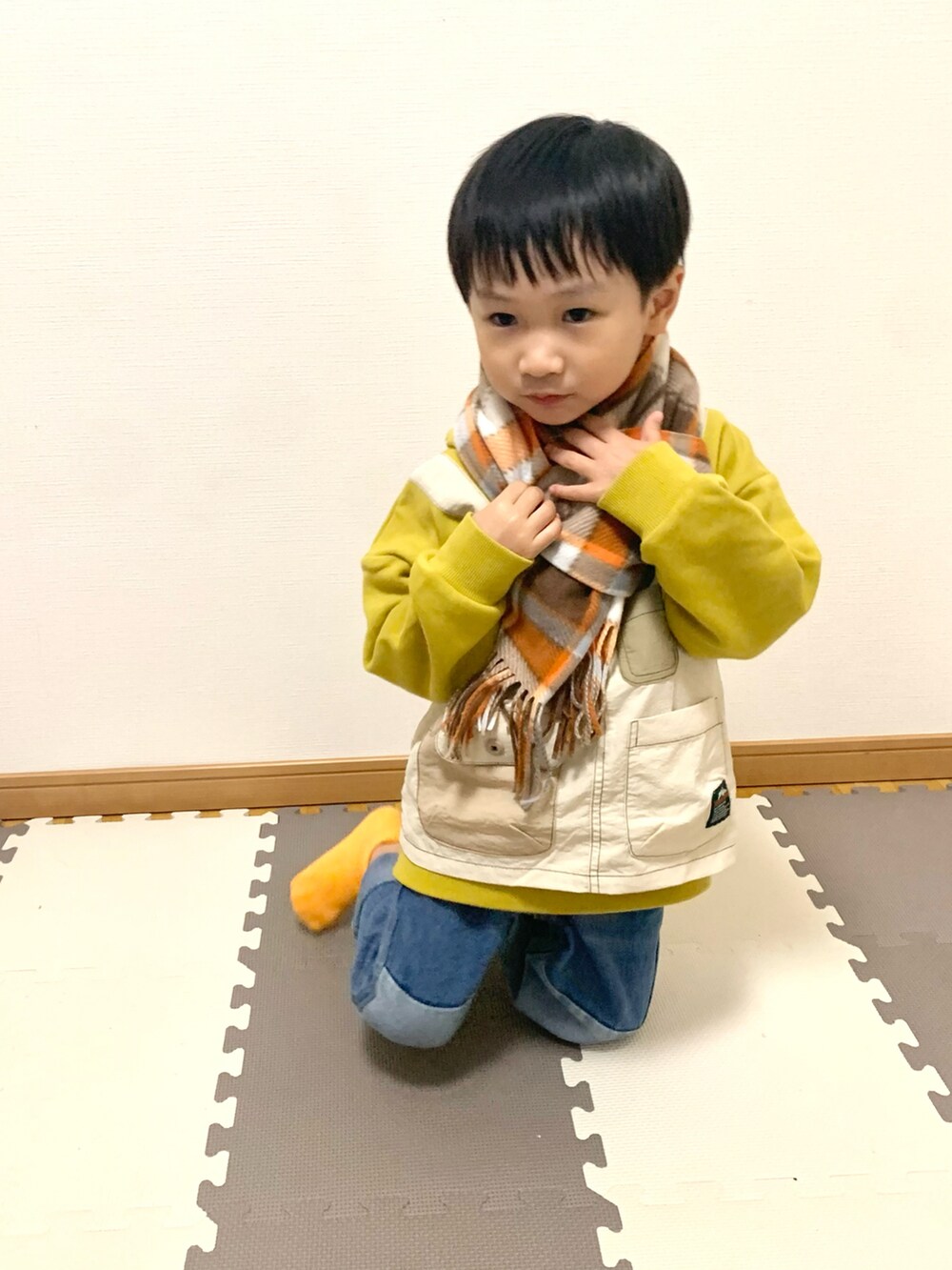 イエロー系のパーカー、ブルー系のデニムパンツ、その他のソックス/靴下を着用したキッズの秋コーディネートの4枚目の写真