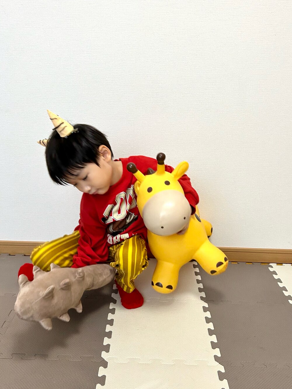 レッド系のスウェット、イエロー系のその他パンツ、ベージュ系のおもちゃを着用したキッズの冬コーディネートの4枚目の写真