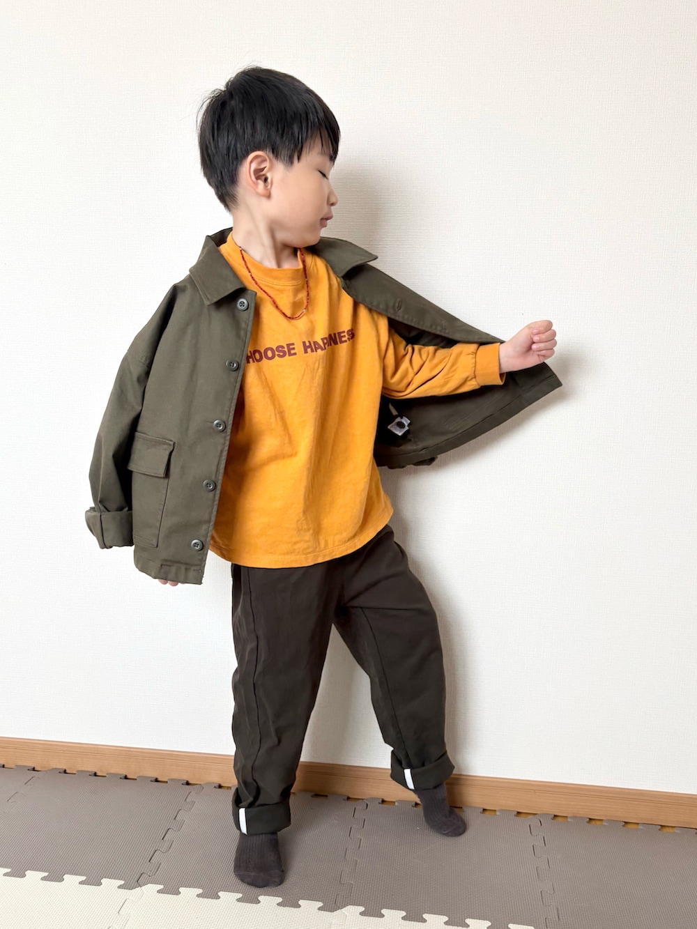 イエロー系のTシャツ/カットソー、グリーン系のジャケット/アウター、ブラウン系のチノパンツを着用したキッズの春コーディネートの3枚目の写真