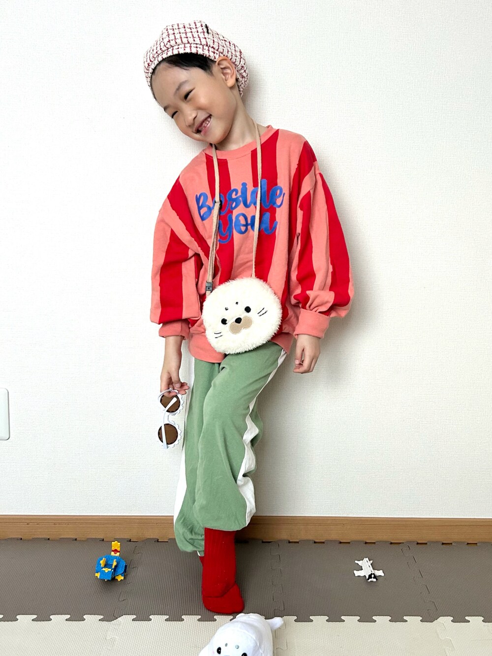 グリーン系のスウェットパンツ、ピンク系のスウェット、ホワイト系のショルダーバッグを着用したキッズの冬コーディネートの3枚目の写真