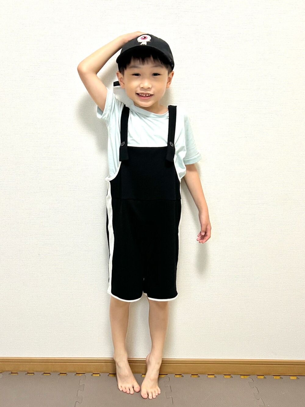 グリーン系のTシャツ/カットソー、ブラック系のサロペット/オーバーオール、ホワイト系のキャップを着用したキッズの夏コーディネートの4枚目の写真
