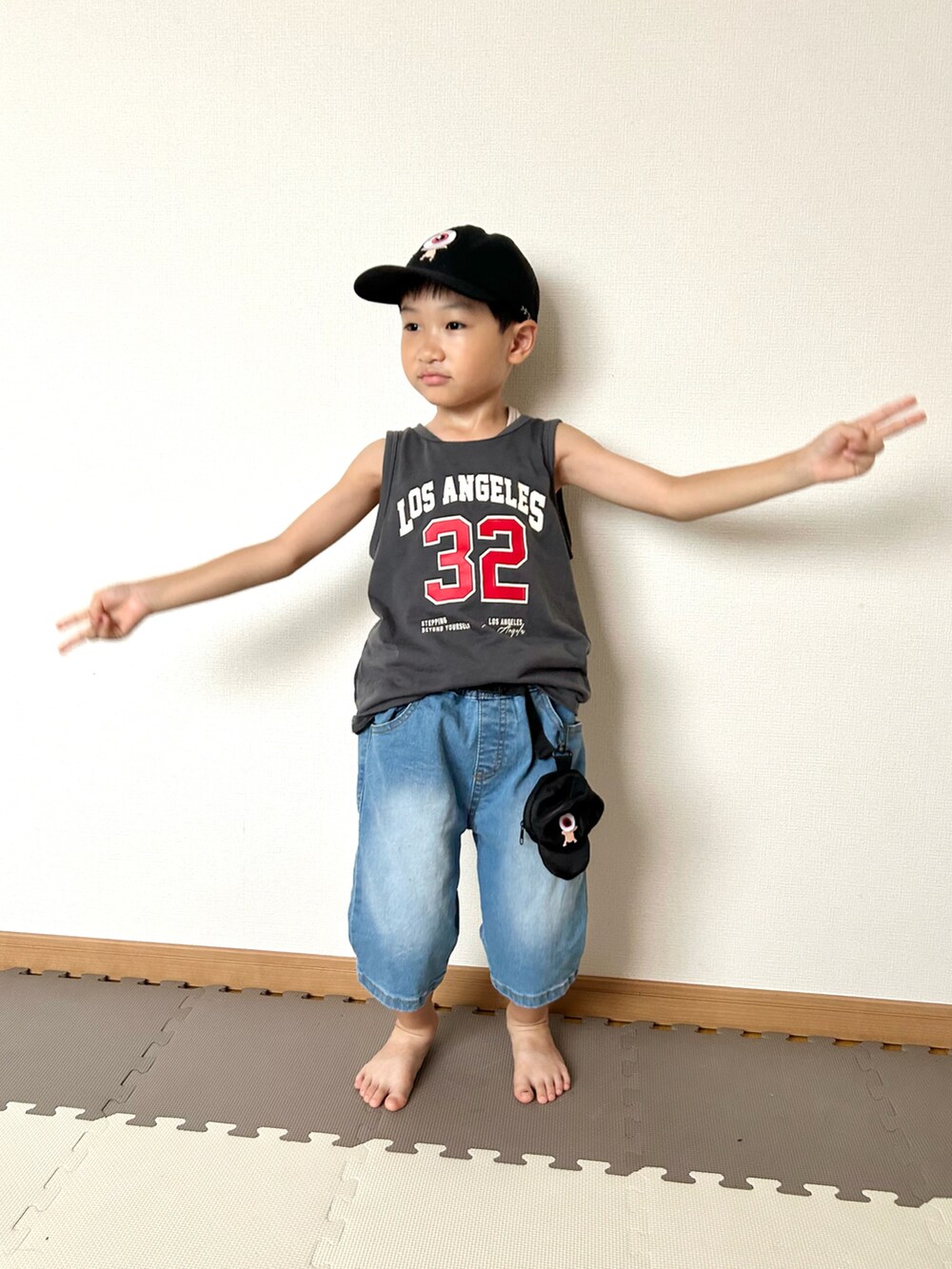 ブルー系のデニムパンツ、グレー系のタンクトップ、ブラック系のバッグを着用したキッズの夏コーディネートの4枚目の写真