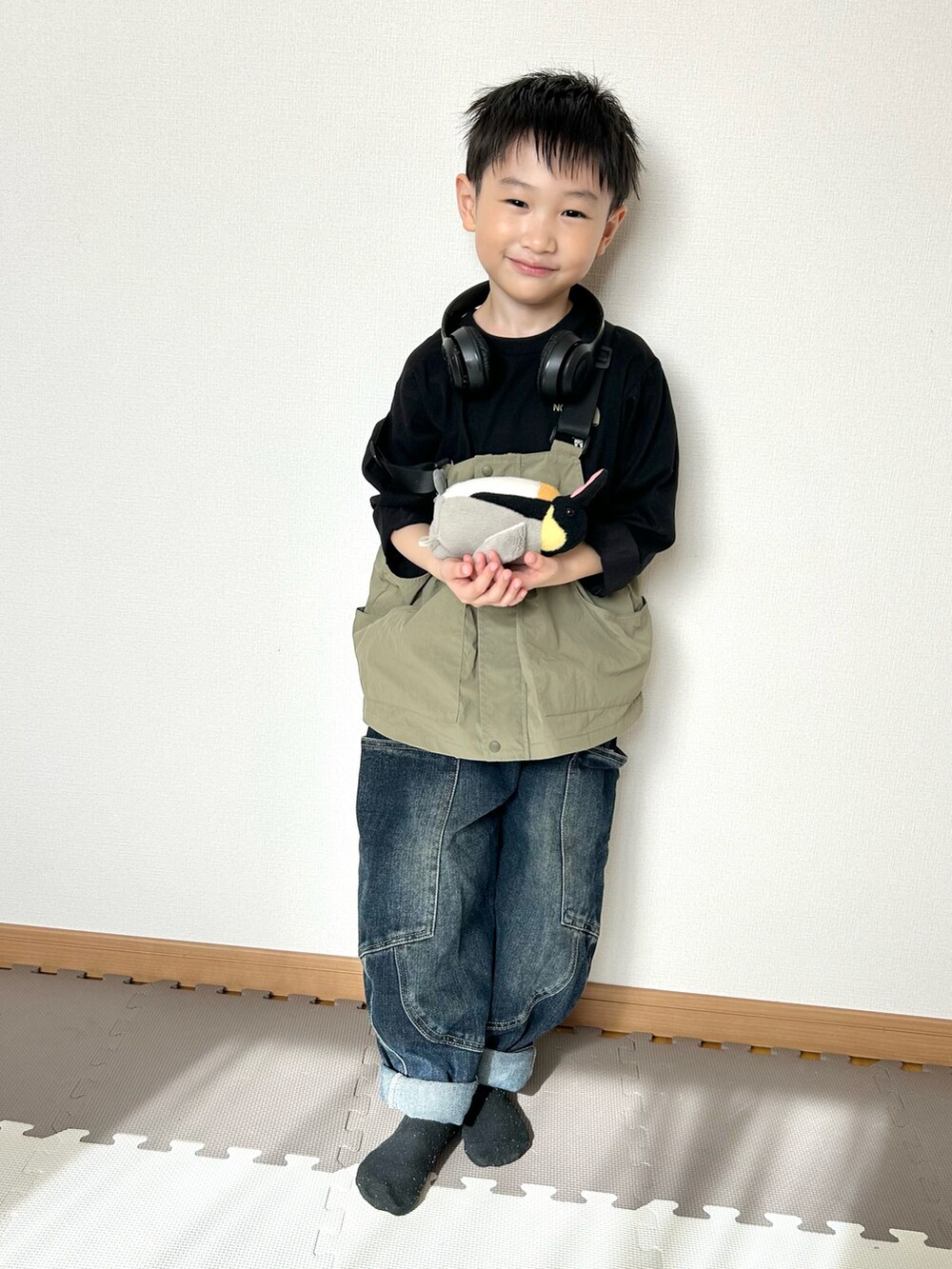 グリーン系のダウンベスト、ブラック系のTシャツ/カットソー、ブラック系のヘッドフォン/イヤホンを着用したキッズの春コーディネートの2枚目の写真