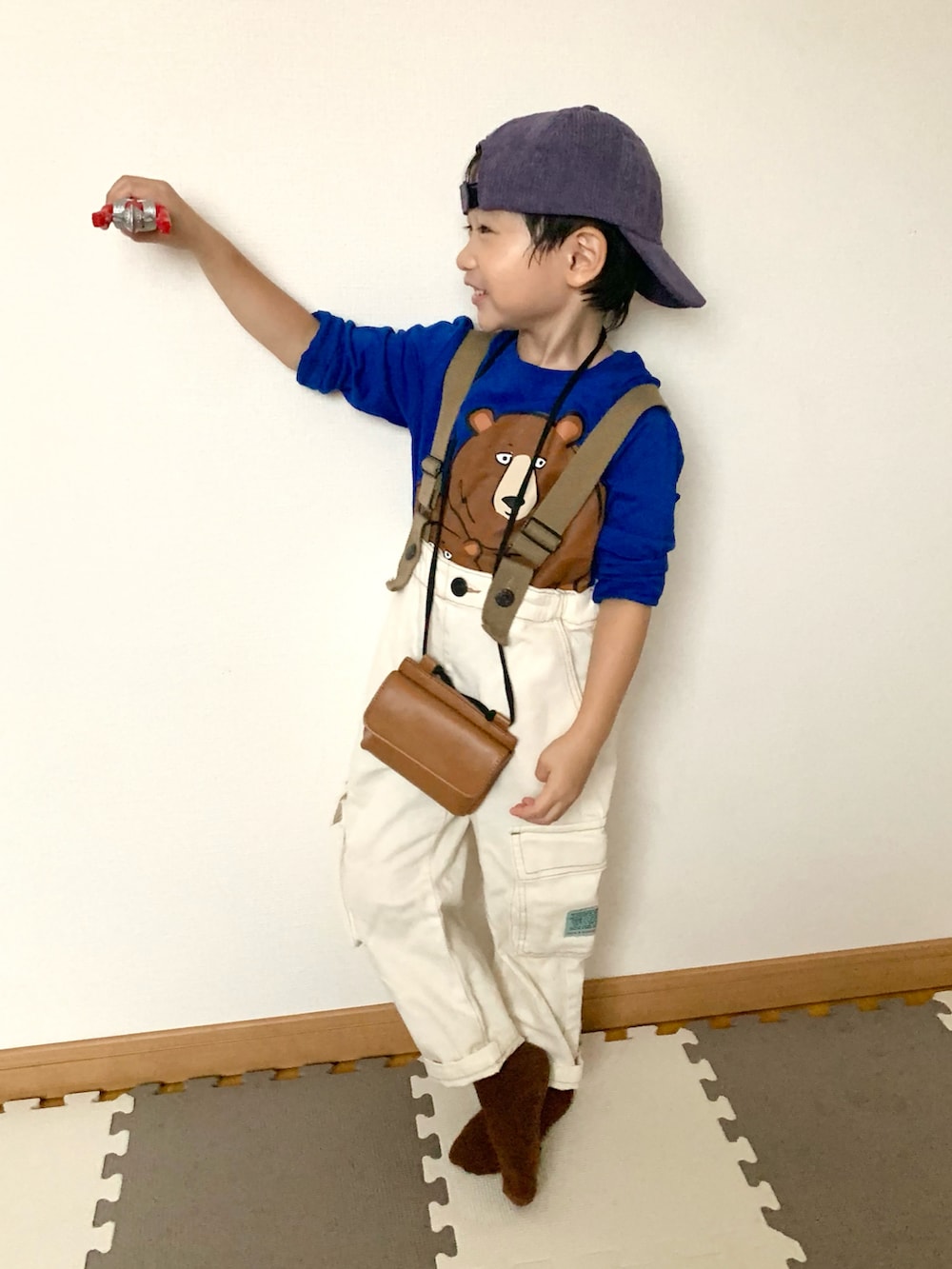 ホワイト系のサロペット/オーバーオール、グリーン系のTシャツ/カットソー、ブラウン系のショルダーバッグを着用したキッズの秋コーディネートの5枚目の写真