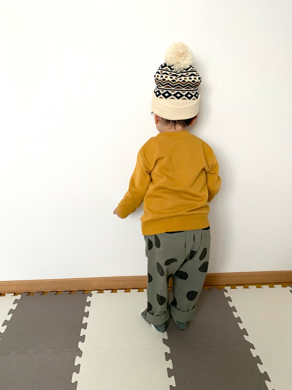 イエロー系のスウェット、グリーン系のその他パンツ、ホワイト系のニットキャップ/ビーニーを着用したキッズの秋コーディネートの3枚目の写真