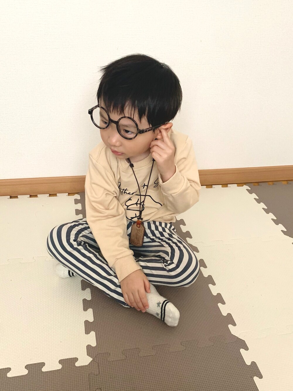 ベージュ系のスウェット、ブルー系のチノパンツ、ブラウン系のネックレスを着用したキッズの春コーディネートの2枚目の写真