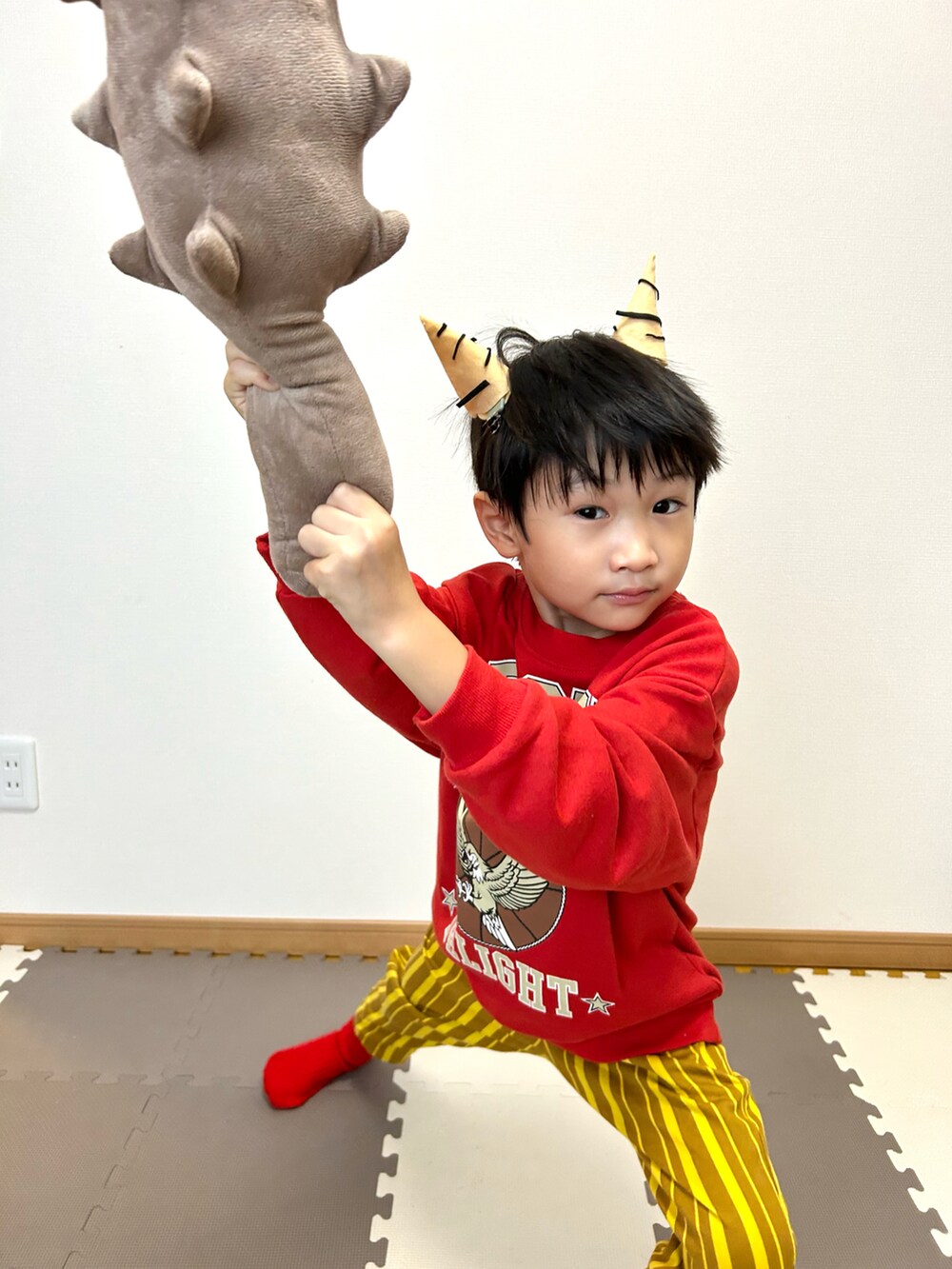 レッド系のスウェット、イエロー系のその他パンツ、ベージュ系のおもちゃを着用したキッズの冬コーディネートの3枚目の写真