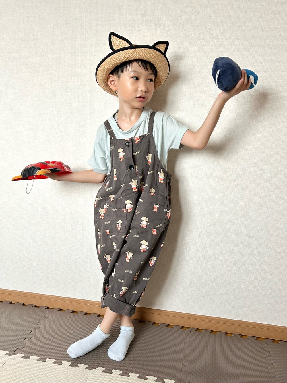 グレー系のサロペット/オーバーオール、グリーン系のTシャツ/カットソー、ベージュ系のハットを着用したキッズの夏コーディネートの2枚目の写真