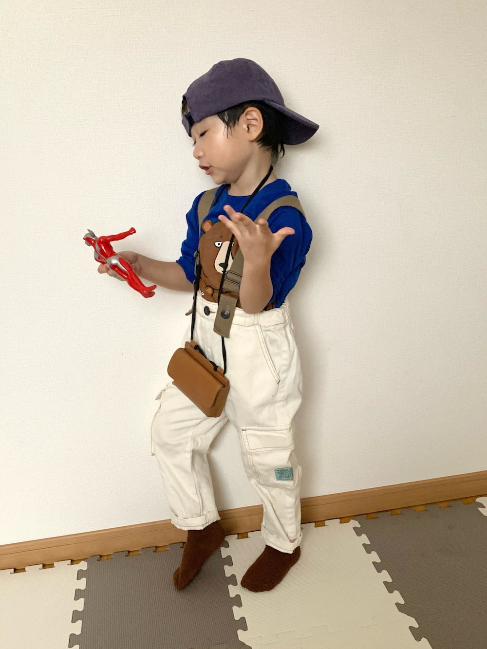 ホワイト系のサロペット/オーバーオール、グリーン系のTシャツ/カットソー、ブラウン系のショルダーバッグを着用したキッズの秋コーディネートの2枚目の写真