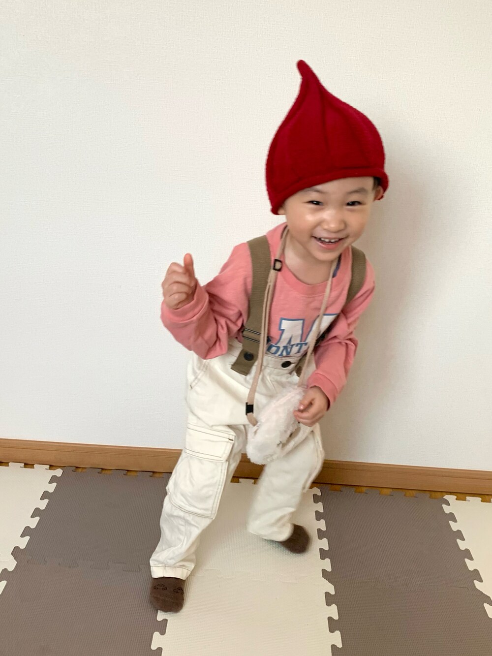 ピンク系のTシャツ/カットソー、ホワイト系のサロペット/オーバーオール、ベージュ系のカーディガン/ボレロを着用したキッズの冬コーディネートの2枚目の写真