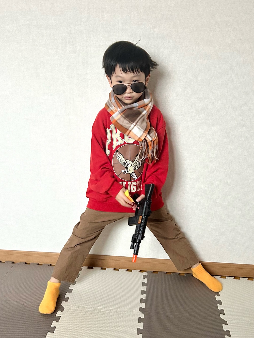 レッド系のスウェット、ブラウン系のパンツ、シルバー系のマフラーを着用したキッズの秋コーディネートの2枚目の写真