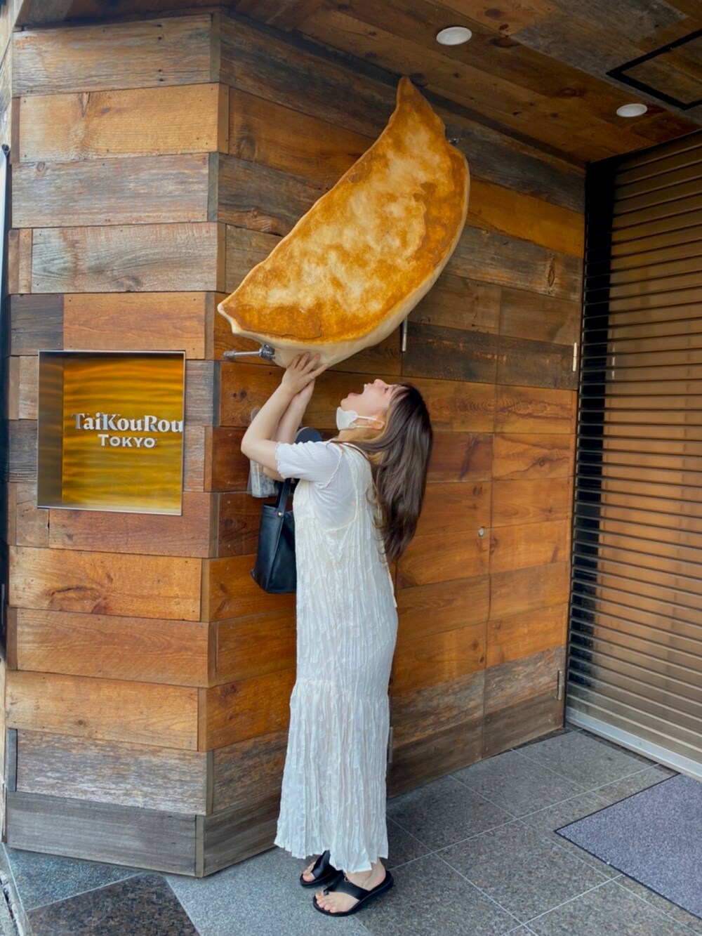 ブラック系のサンダル、ベージュ系のワンピース、ホワイト系のTシャツ/カットソーを着用したレディースの夏コーディネートの2枚目の写真