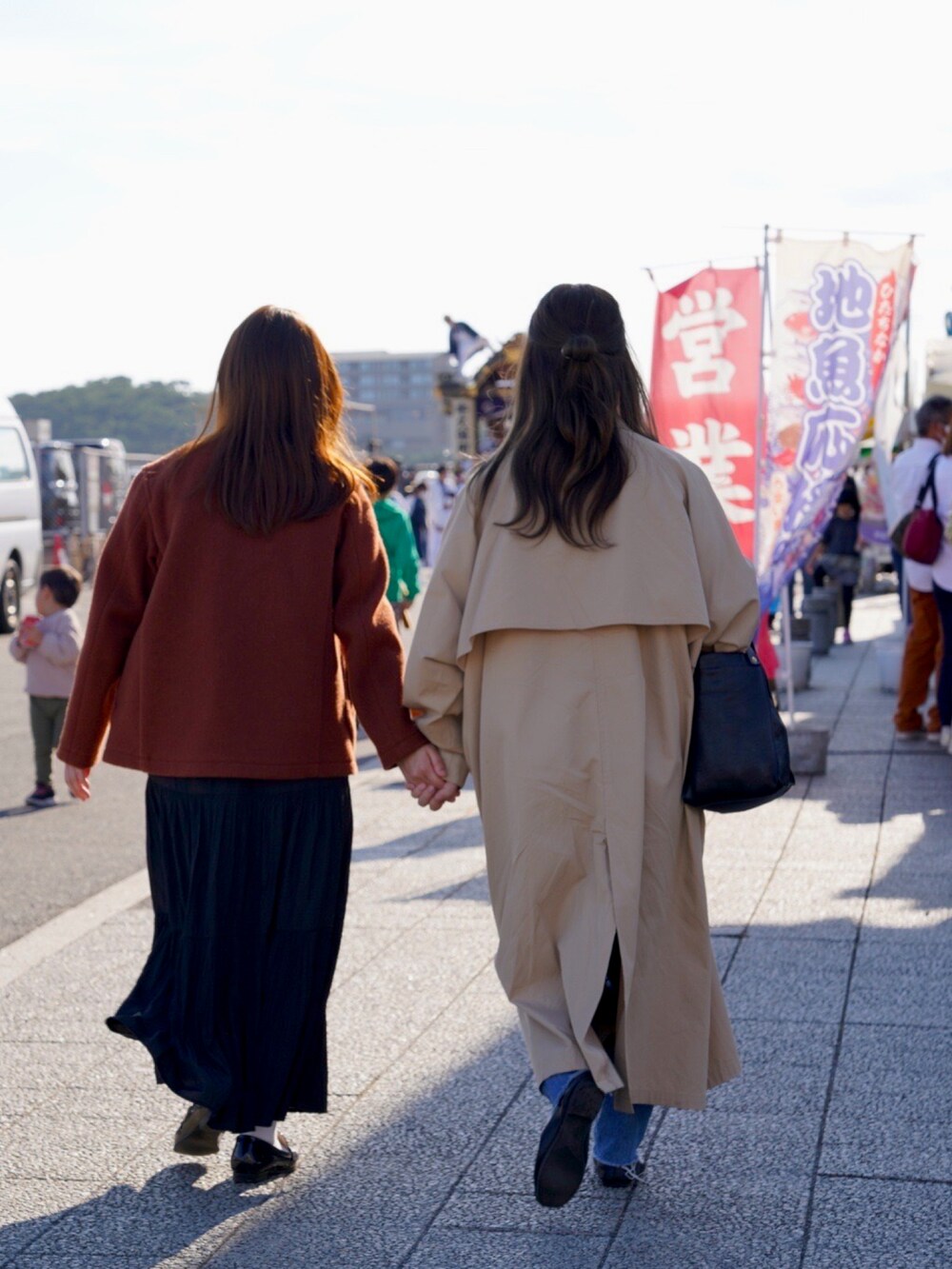 ベージュ系のトレンチコート、ブルー系のデニムパンツ、レッド系のニット/セーターを着用したレディースの秋コーディネートの3枚目の写真