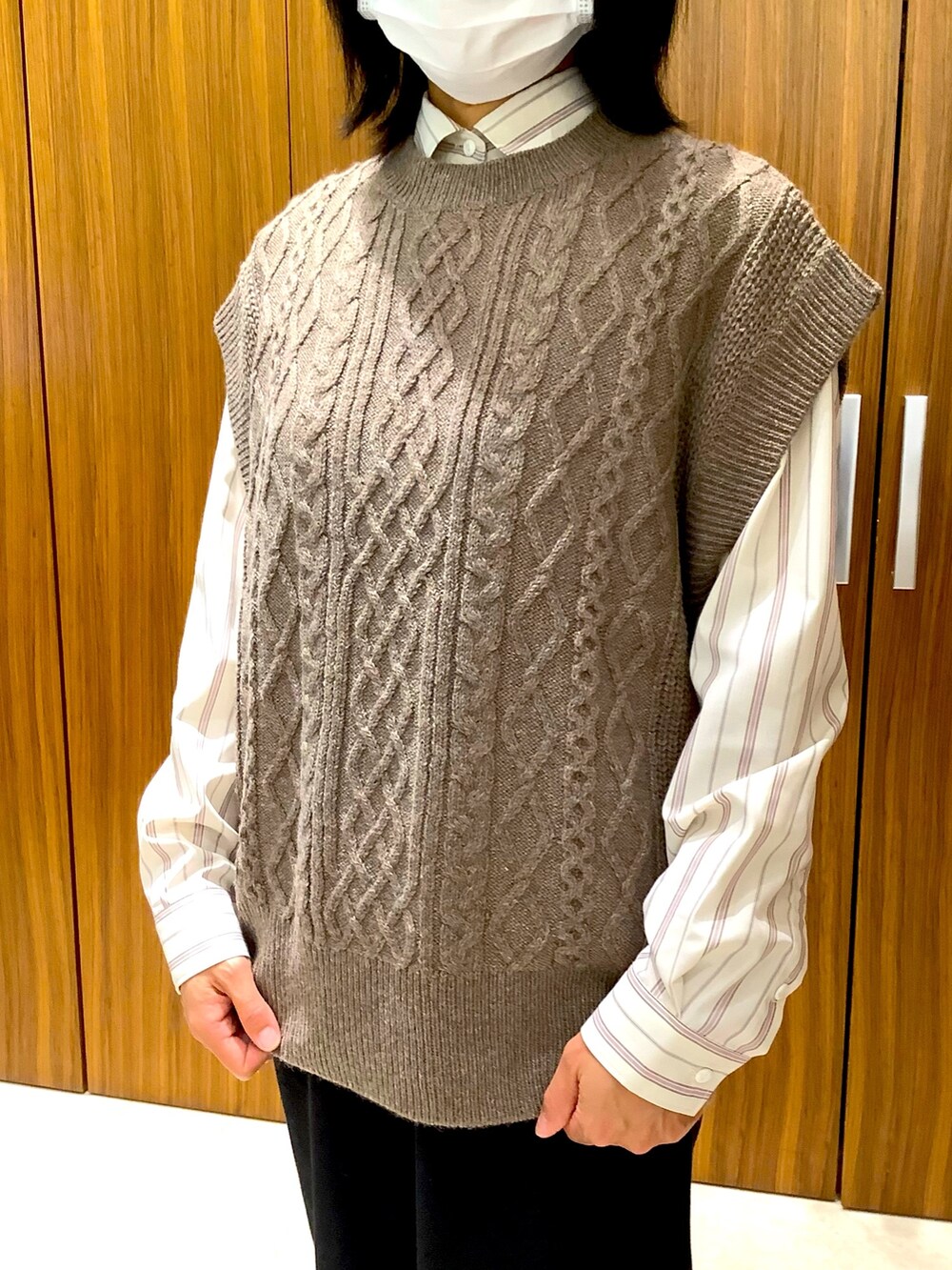 ベージュ系のビジネスシャツ、ブラウン系のベストを着用したレディースの秋コーディネートの2枚目の写真