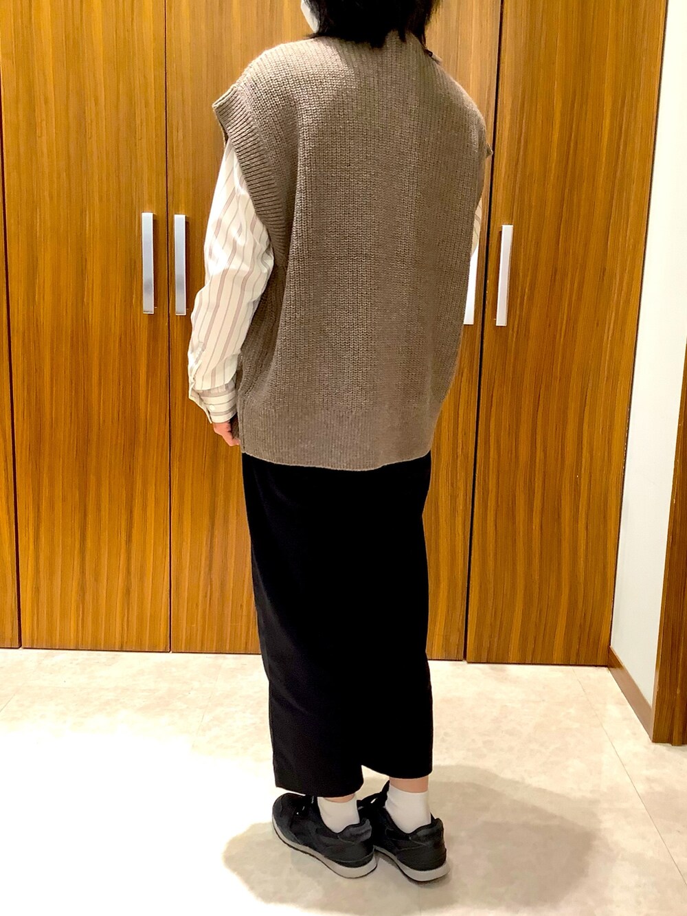 ベージュ系のビジネスシャツ、ブラウン系のベストを着用したレディースの秋コーディネートの3枚目の写真