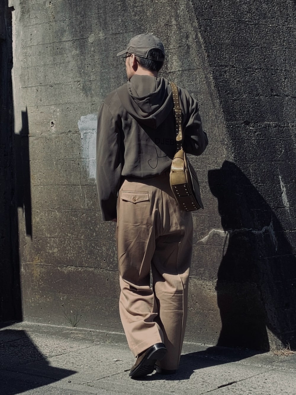 グレー系のパーカー、ベージュ系のスラックス、グリーン系のブーツを着用したメンズの春コーディネートの4枚目の写真