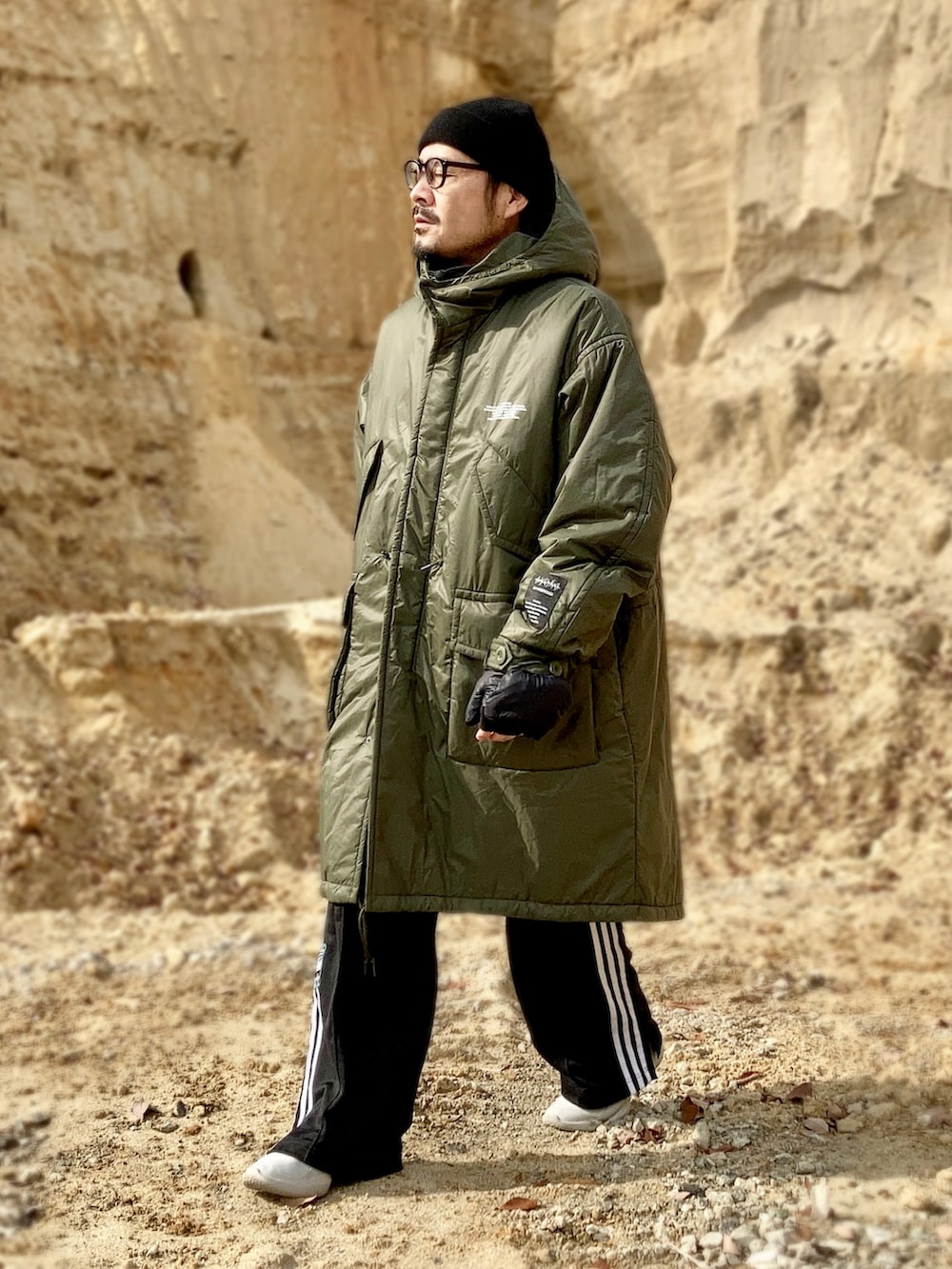 ブルー系のTシャツ/カットソー、ブラック系のベスト、グリーン系のミリタリージャケットを着用したメンズの冬コーディネートの2枚目の写真