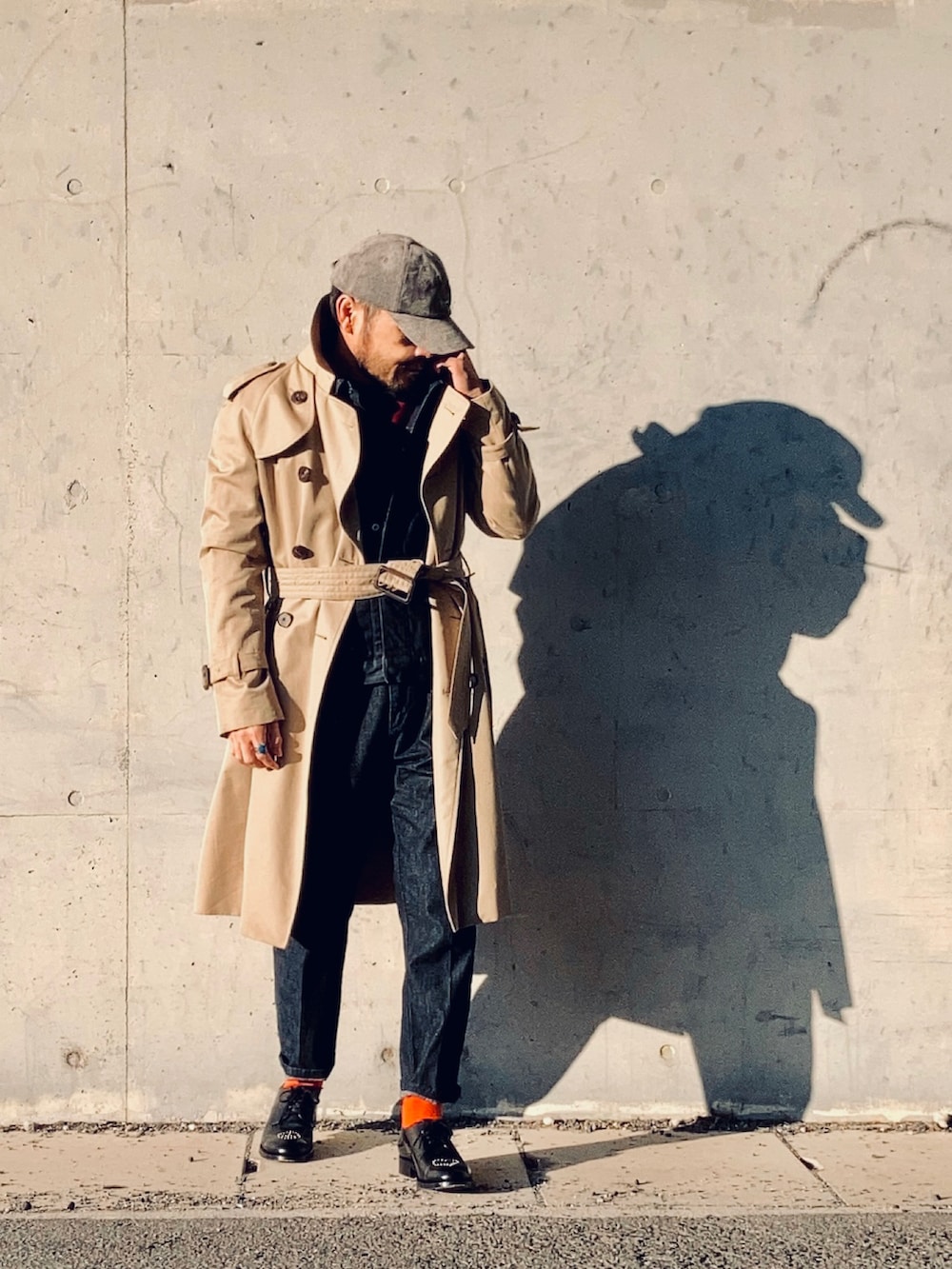 レッド系のニット/セーター、ブルー系のデニムジャケット、ベージュ系のトレンチコートを着用したメンズの冬コーディネートの4枚目の写真