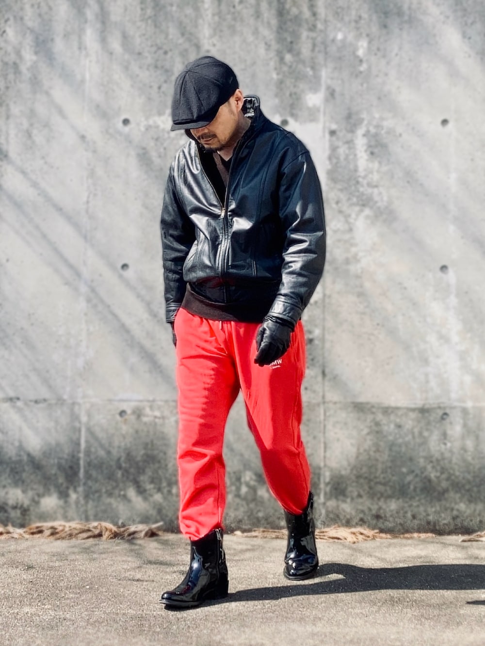レッド系のスウェットパンツ、ブラック系のブルゾン、ブラック系のブーツを着用したメンズの春コーディネートの2枚目の写真