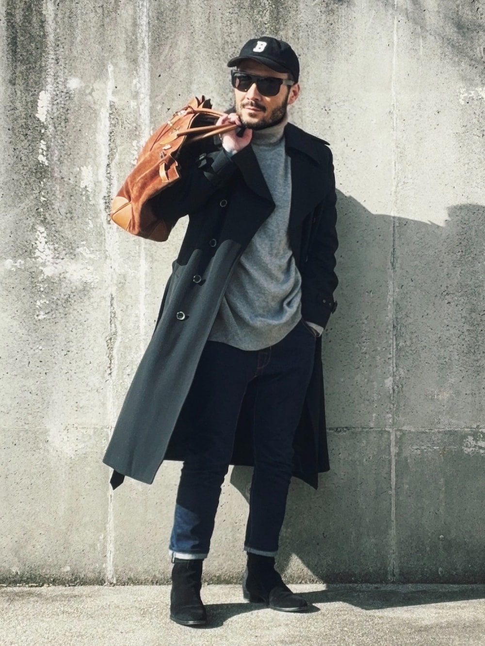 グレー系のニット/セーター、ブラック系のブーツ、ブラック系のトレンチコートを着用したメンズの冬コーディネートの2枚目の写真