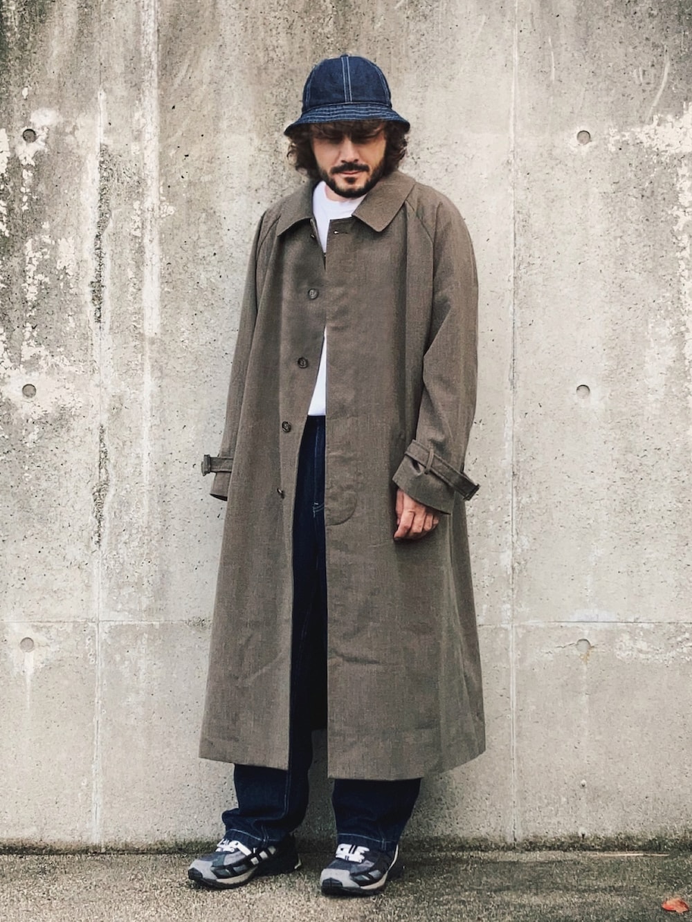 グレー系のステンカラーコート、ホワイト系のTシャツ/カットソー、ブルー系のデニムパンツを着用したメンズの秋コーディネートの2枚目の写真