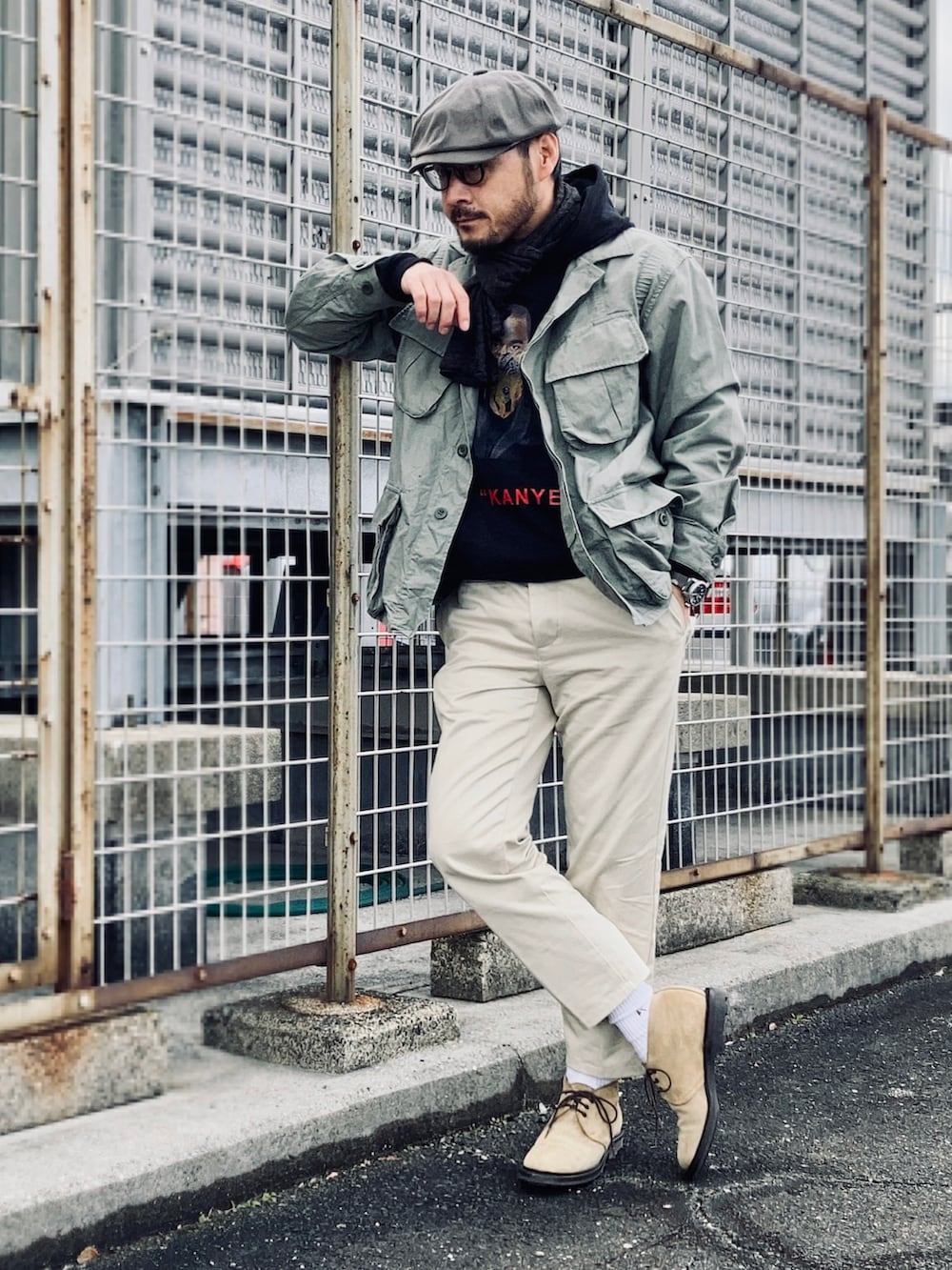 ブラック系のパーカー、グリーン系のミリタリージャケット、ベージュ系のチノパンツを着用したメンズの冬コーディネートの3枚目の写真