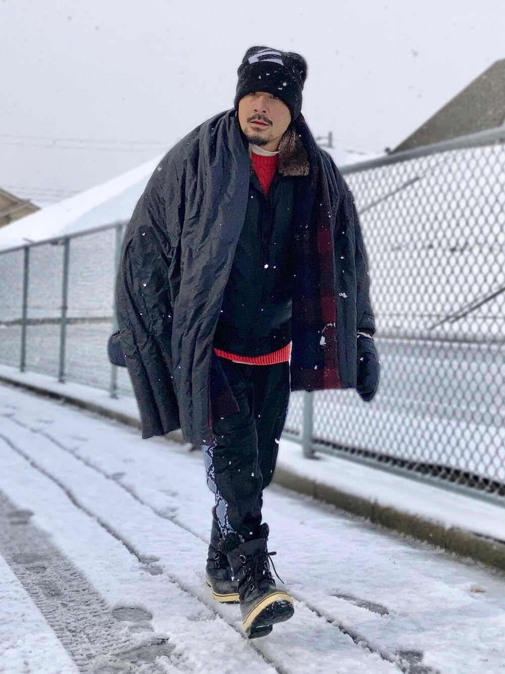 ベージュ系のTシャツ/カットソー、レッド系のニット/セーター、ブラック系のダウンジャケット/コートを着用したメンズの冬コーディネートの2枚目の写真