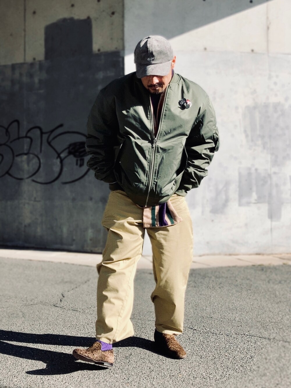 ベージュ系のTシャツ/カットソー、パープル系のスウェット、グリーン系のMA-1を着用したメンズの冬コーディネートの4枚目の写真