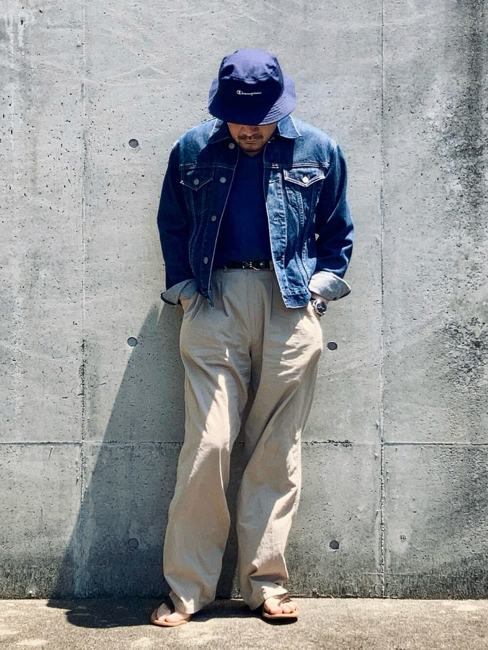 ブルー系のデニムジャケット、ベージュ系のスラックス、ブラウン系のサンダルを着用したメンズの春コーディネートの2枚目の写真