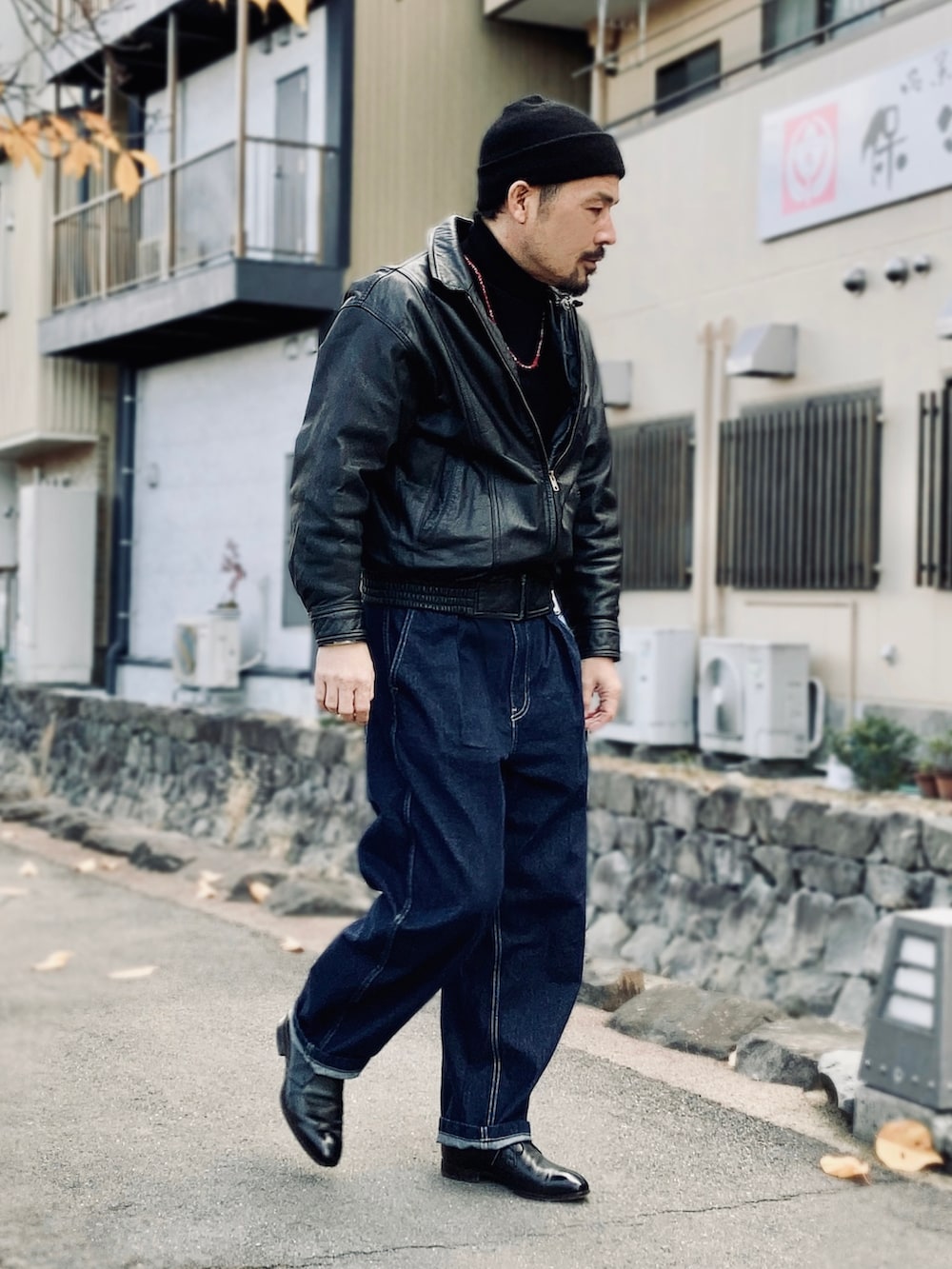 ブラック系のニット/セーター、ブラック系のブルゾン、ブルー系のデニムパンツを着用したメンズの冬コーディネートの3枚目の写真