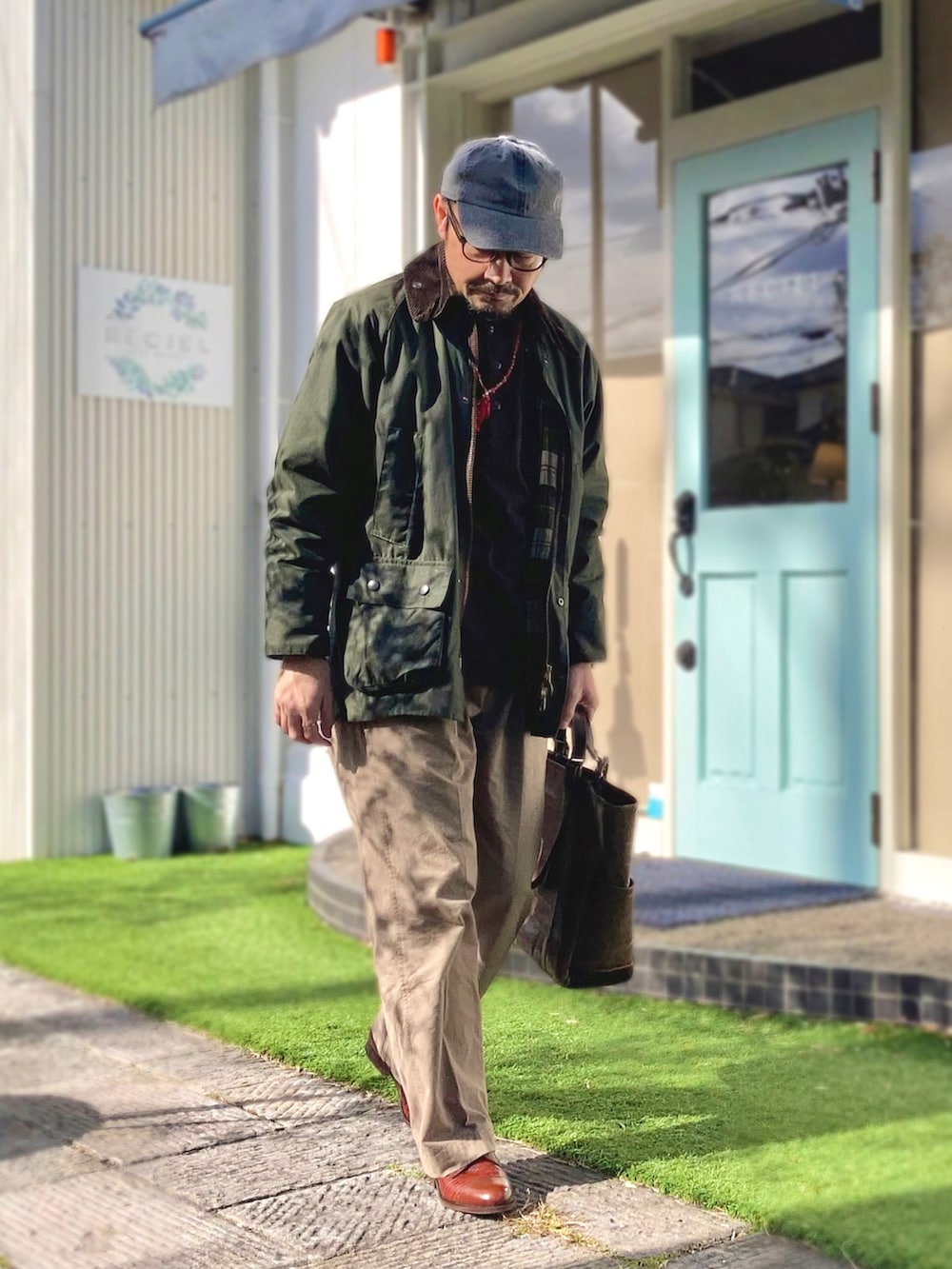 ブラウン系のTシャツ/カットソー、グリーン系のその他アウター、ベージュ系のチノパンツを着用したメンズの冬コーディネートの2枚目の写真