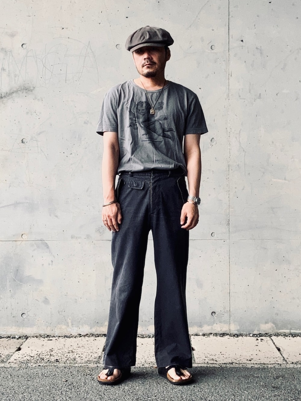 グレー系のTシャツ/カットソー、グレー系のスラックス、ブラック系のサンダルを着用したメンズの夏コーディネートの3枚目の写真