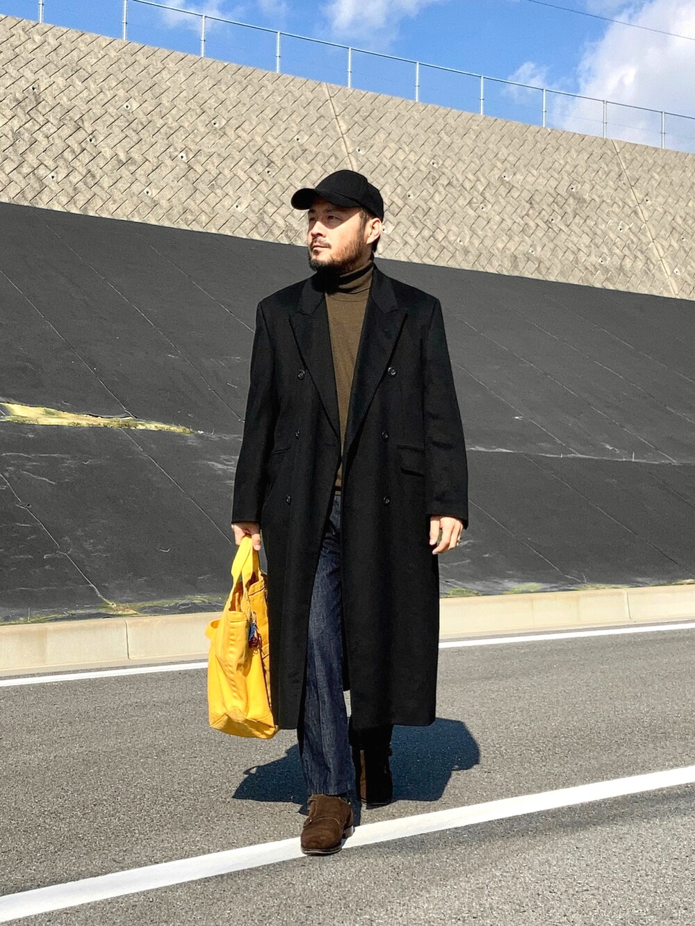 ブラック系のチェスターコート、ブルー系のデニムパンツ、ブラウン系のドレスシューズを着用したメンズの秋コーディネートの2枚目の写真