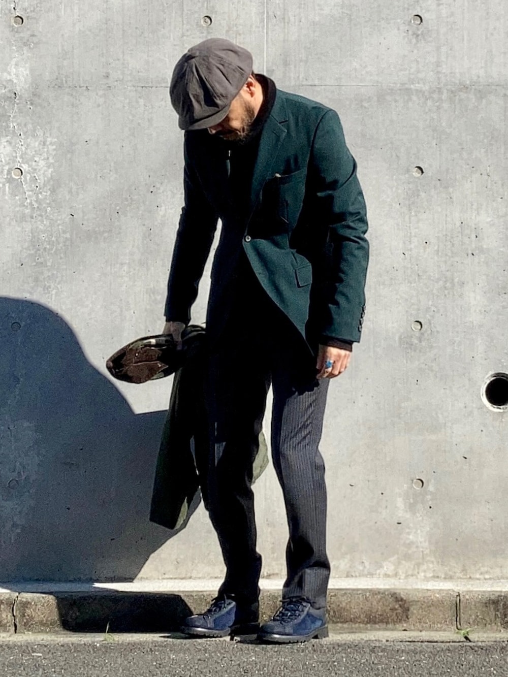 ブラック系のニット/セーター、グリーン系のテーラードジャケット、グレー系のスラックスを着用したメンズの冬コーディネートの2枚目の写真